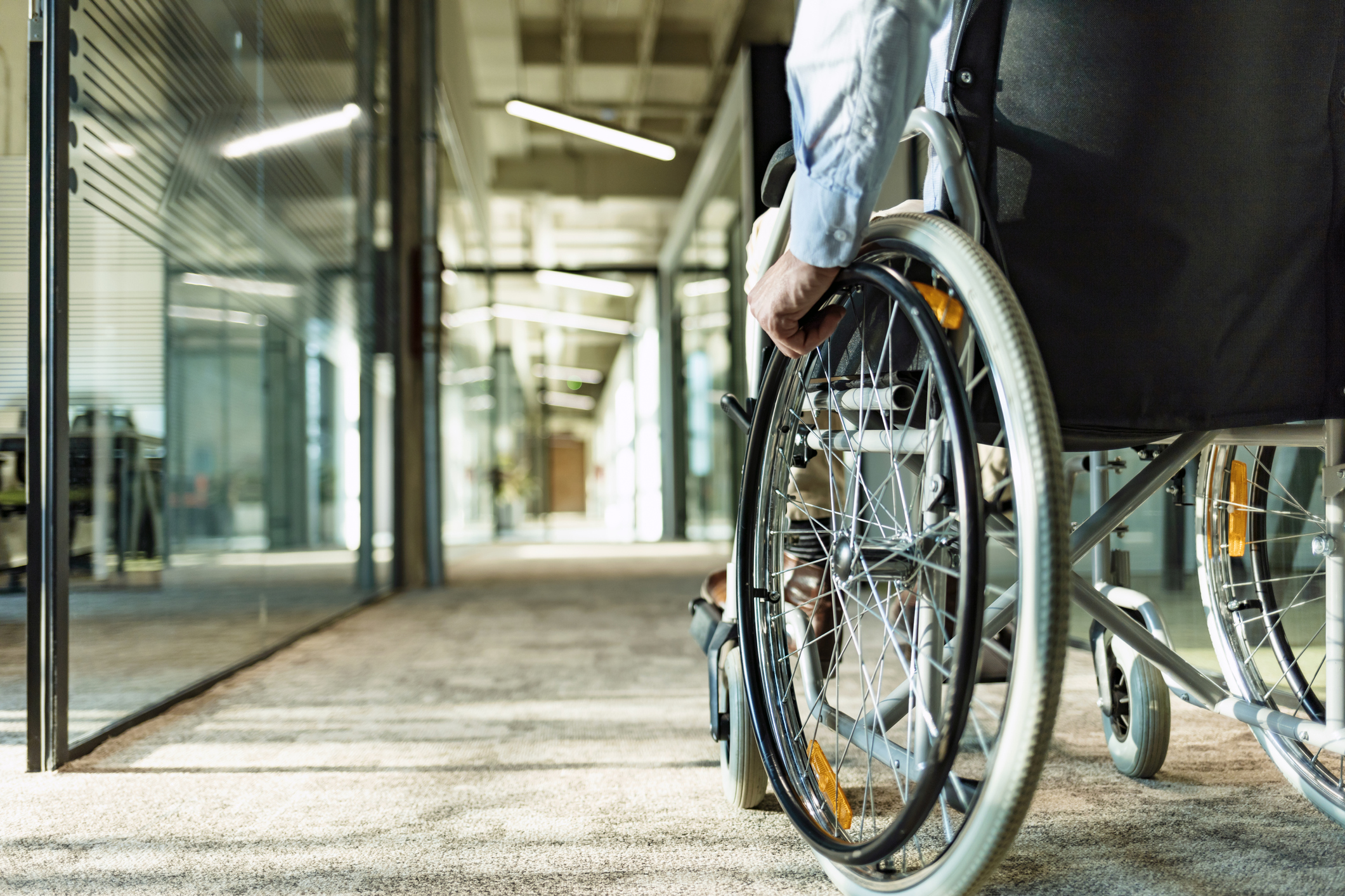 Homme paralysé en fauteuil roulant en déplacement dans l'immeuble de bureaux pour personnes handicapées.